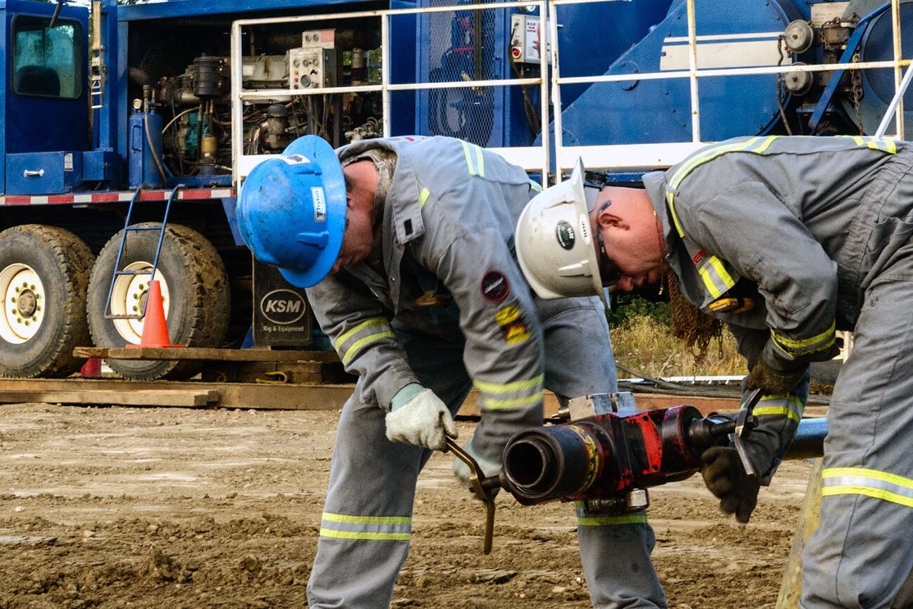 Two Bullet Wireline crew members handling downhole tools at the wellhead
